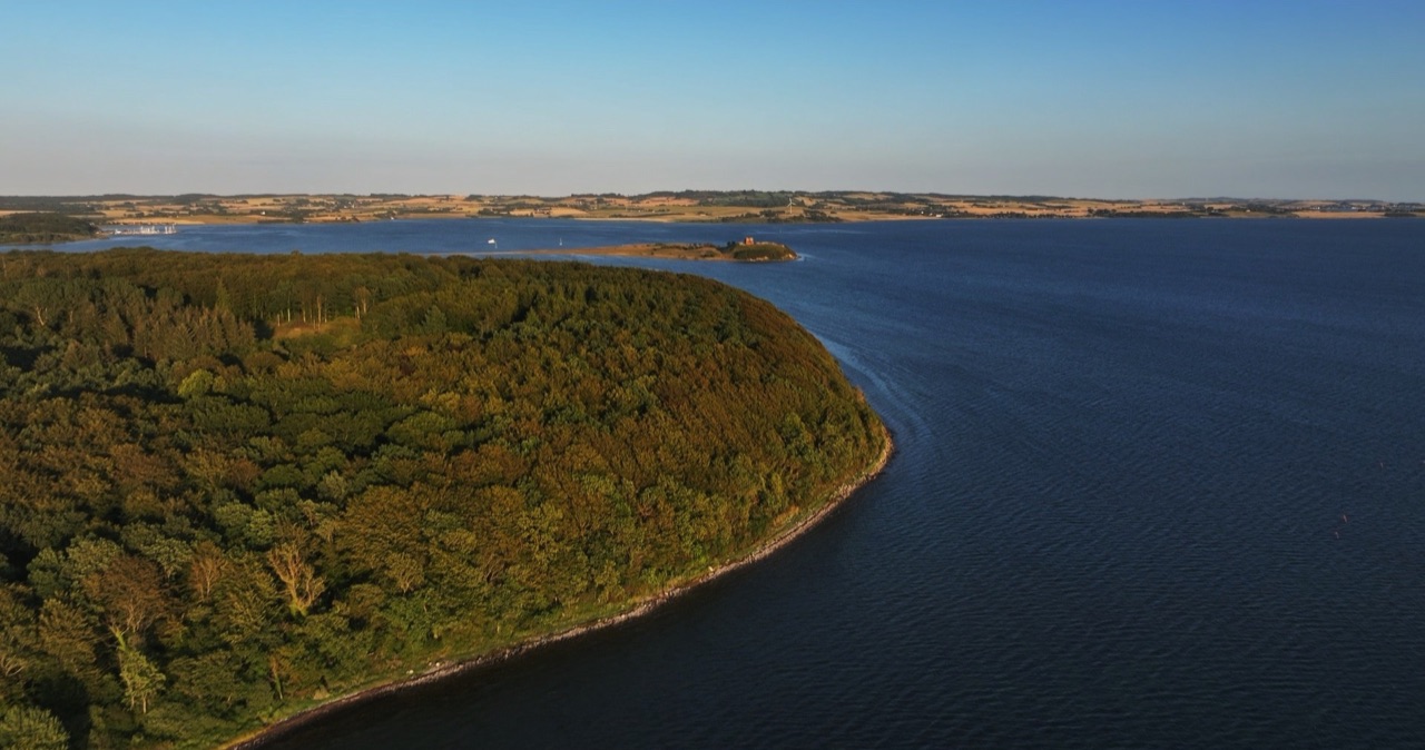 Kyst og fjord i aftenlys fotograferet fra luften