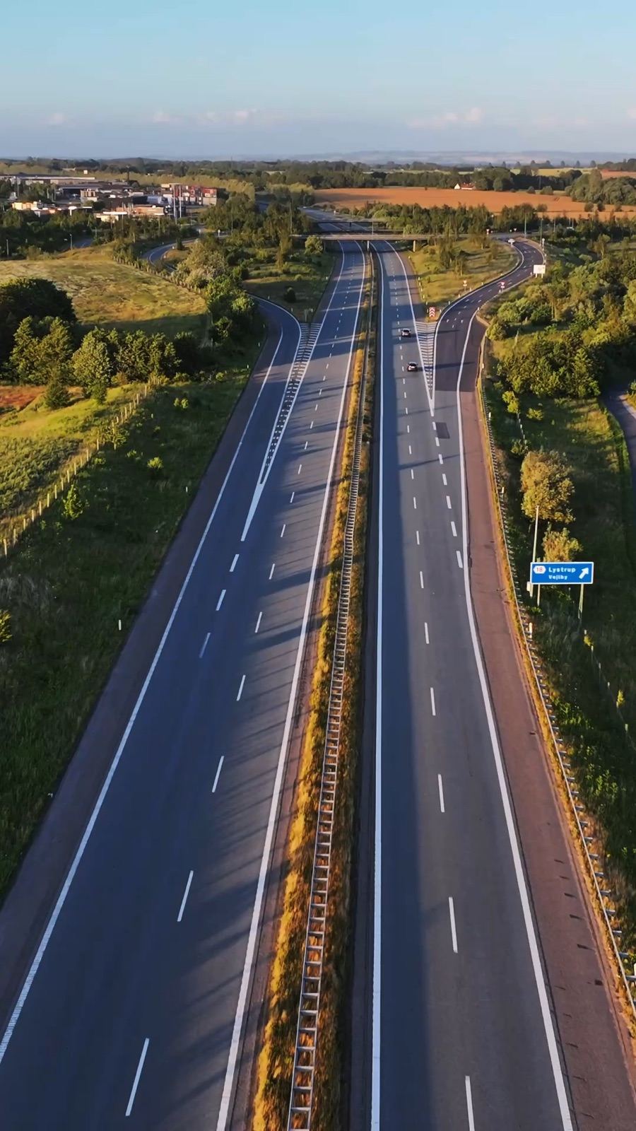 Motorvej gennem landskab i lavt aftenlys set fra luften