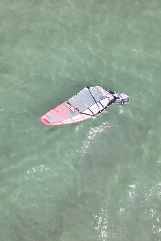 Windsurfer set lodret oppefra over klart, grønt vand